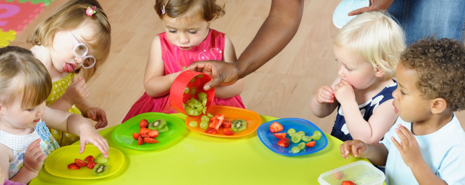 Pre-school children sitting at a table eating fruit