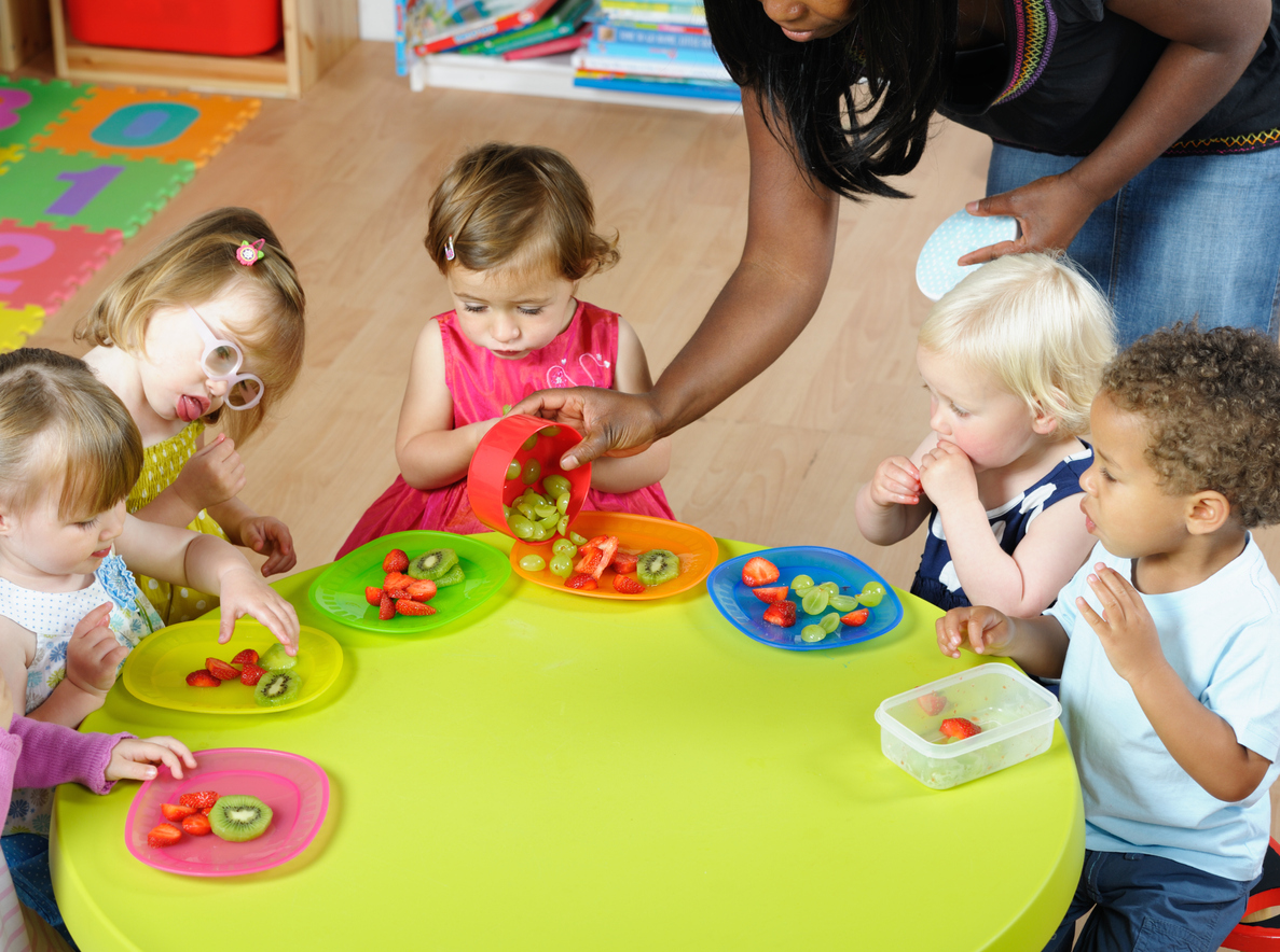 Pre-school children sitting at a table eating fruit
