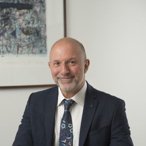 Middle-aged man wearing a sui tjacket and tie at a desk