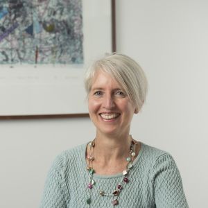 Middle-aged woman weargin a green top sitting at a desk