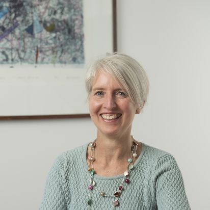 Middle-aged woman weargin a green top sitting at a desk