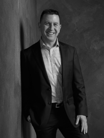 Smiling man in a suit leaning against a wall