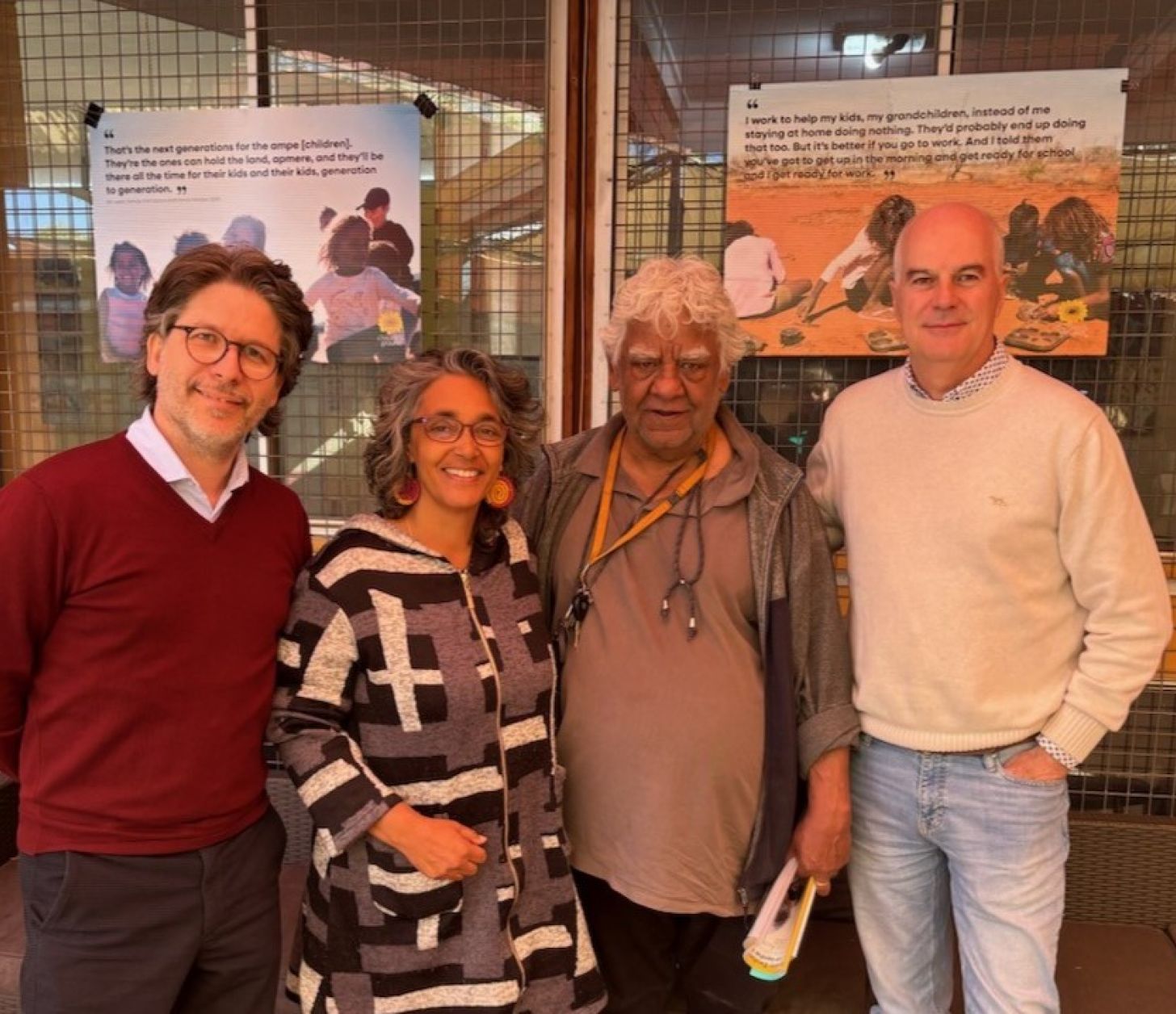 Three men and one woman standing next to each other facing the camera smiling. 