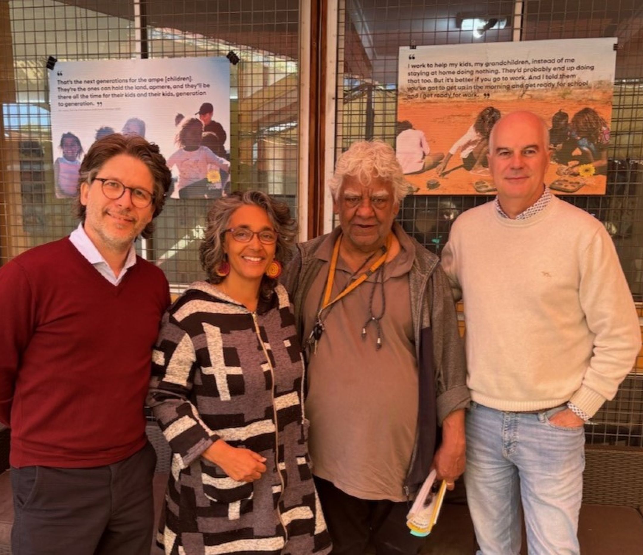 Three men and one woman standing next to each other facing the camera smiling. 