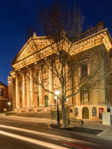 Night shot of illuminated building with classic greek architecture columned facade
