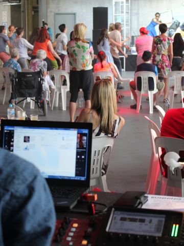 Person at sound mixing board watching musicians on stage