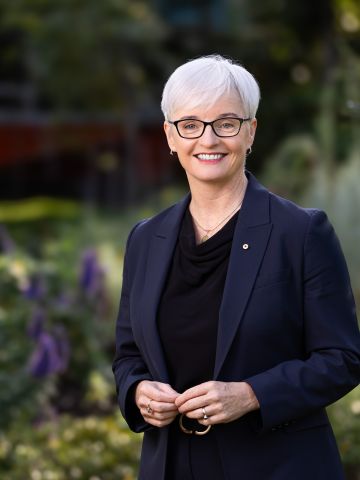 Middle-aged woman in dark jacket facing the camera and smiling