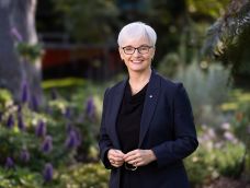 Middle-aged woman in dark jacket facing the camera and smiling