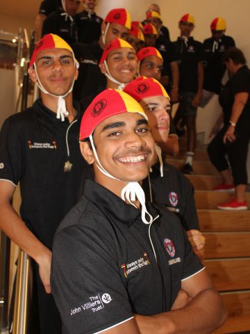 Line of Indigeous male students wearing surf life saving caps