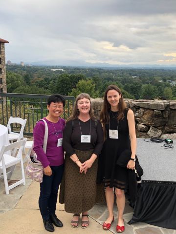 Three women on balcony wth a forest behind them