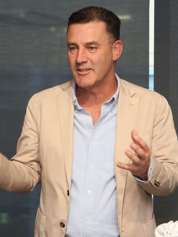 Middle-aged man in a short and jacket gesturing as he speaks to an audience