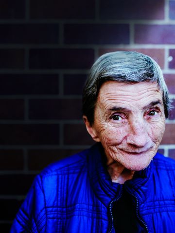 Elderly woman standing in front of a brick wall