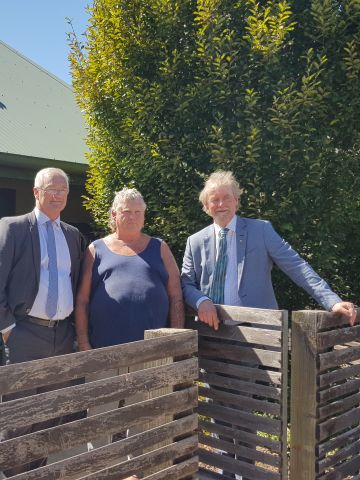 Three men standing in front of a small house