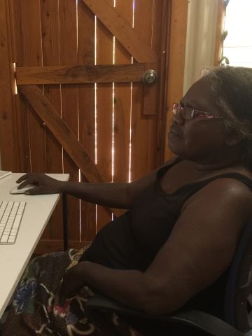 Indigenous woman sitting at desk looking at large computer screen