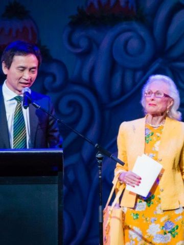 Man at podium with two women next to him.
