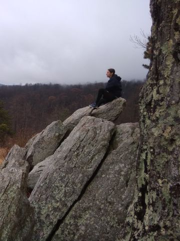 Woman sitting on large granite boulders overlooking forest