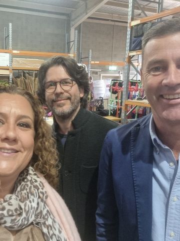 Two women and two men standing in front of warehouse shelvingg