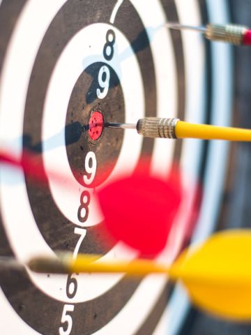Dartboard with 4 darts sticking into it at various distances from the middle