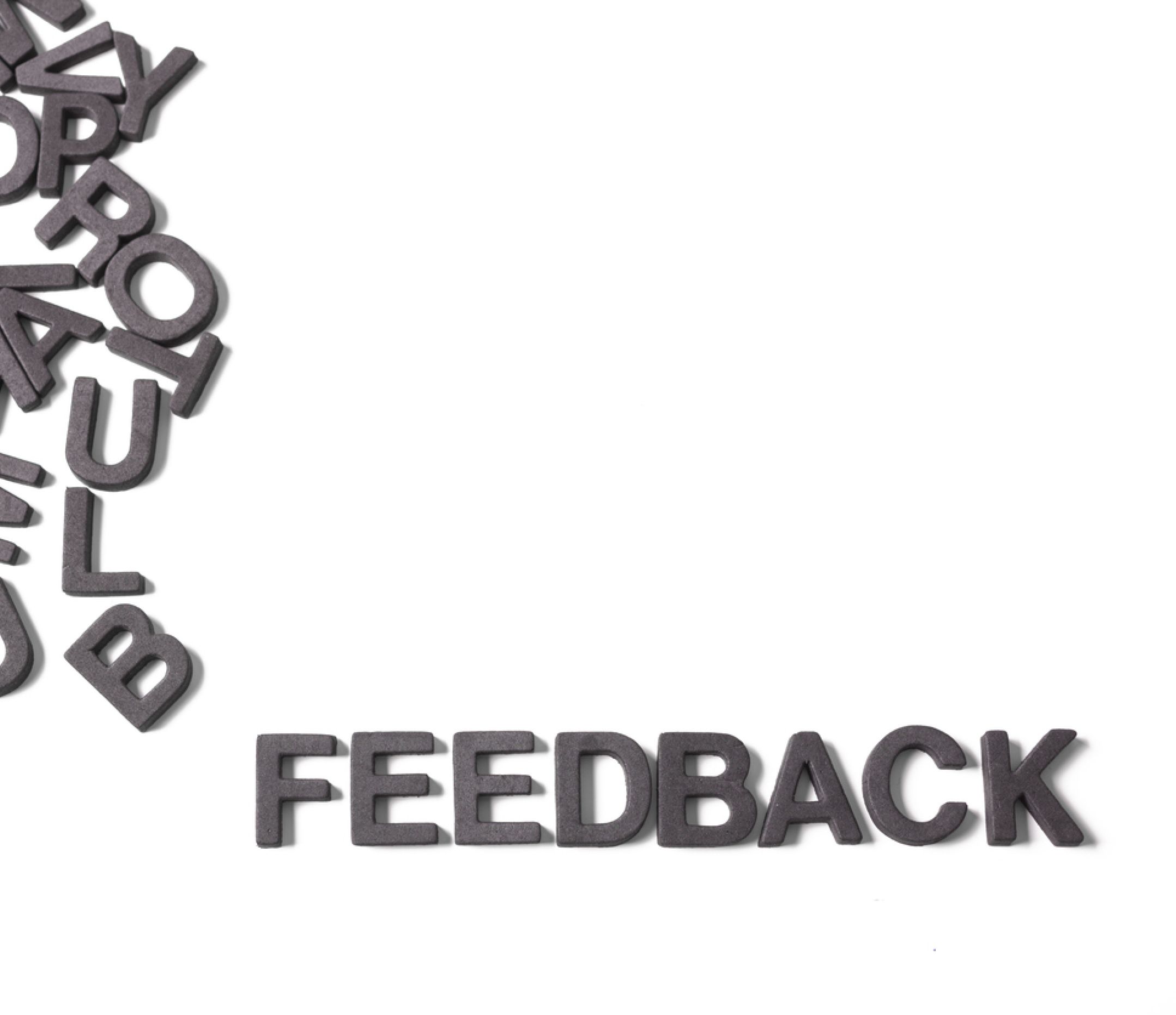 Cut-out jumbled alphabet letters with the word Feedback pulled out